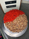 Red velvet layer cake topped with pecans and red velvet crumbs
